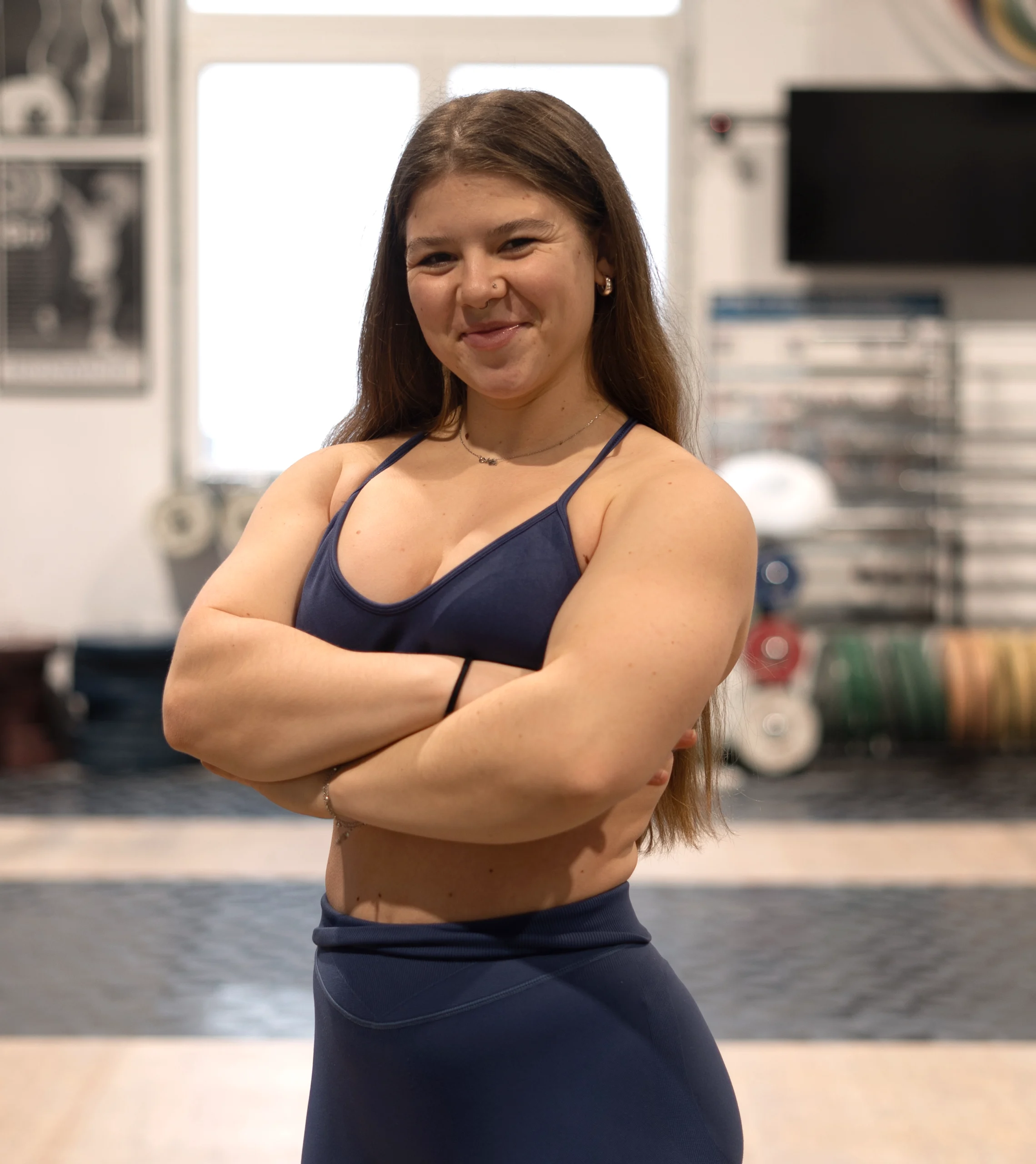 Personal Trainerin bei Star Coaching in Wien im Fitnessstudio, lächelnd mit verschränkten Armen