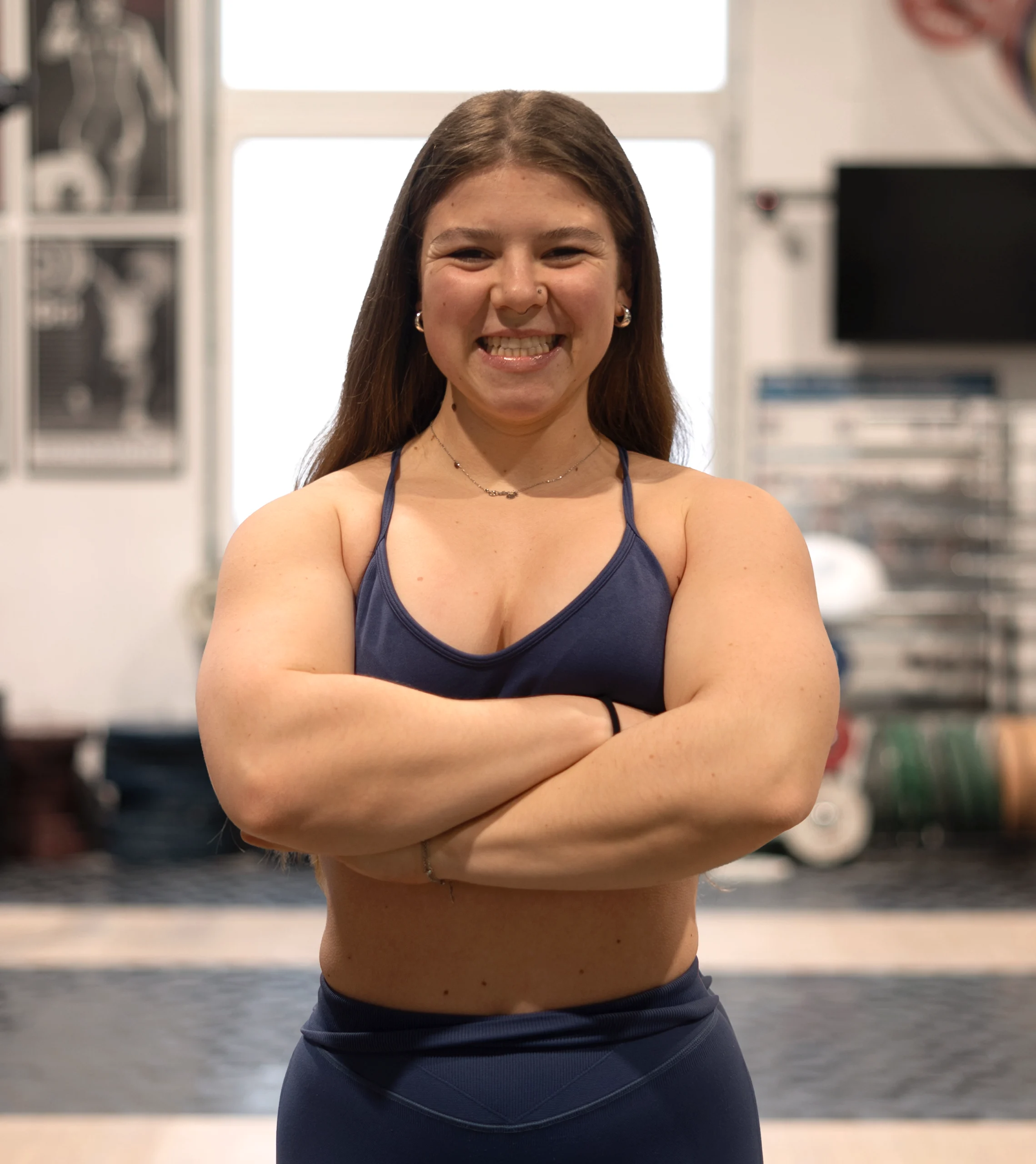 Personal Trainerin bei Star Coaching in Wien im Fitnessstudio, lächelnd mit verschränkten Armen